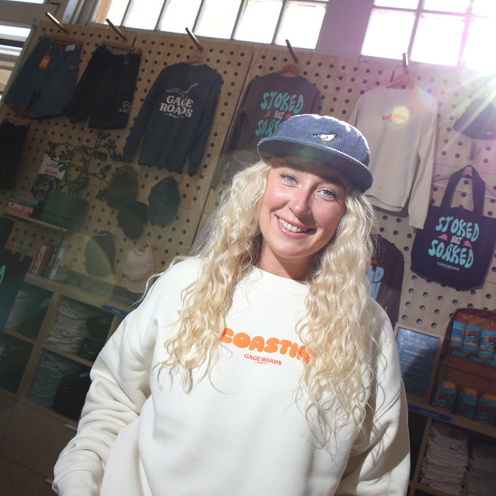 Person wearing a white sweatshirt with orange text in a store setting