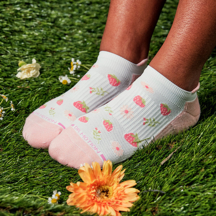 Ankle compression socks with a strawberry pattern, featuring a pink toe and heel, displayed on grass.