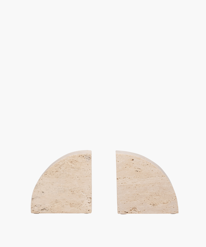 Two beige, semi-circular travertine bookends with textured surfaces are placed against a white background, separated by a small gap, creating a minimalist design. | SW Home