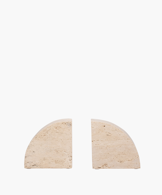 Two beige, semi-circular travertine bookends with textured surfaces are placed against a white background, separated by a small gap, creating a minimalist design. | SW Home