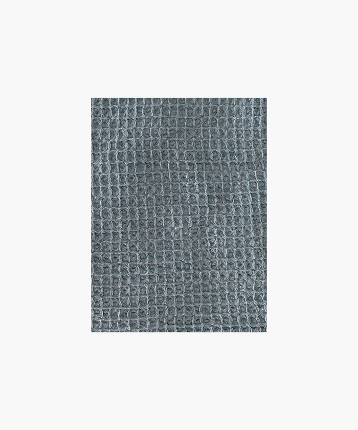 Close up of the vintage blue waffle-textured throw blanket highlighting the texture and color. The soft material conveys a cozy, inviting feel. Suitable for any living room or bedroom.