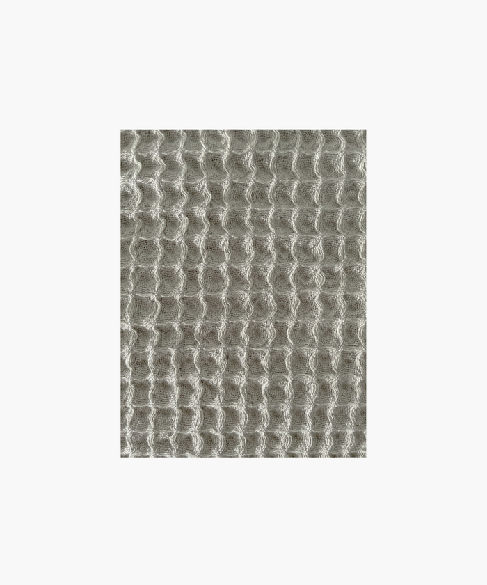 Close up of the olive waffle-textured throw blanket highlighting the texture and color. The soft material conveys a cozy, inviting feel. Suitable for any living room or bedroom.