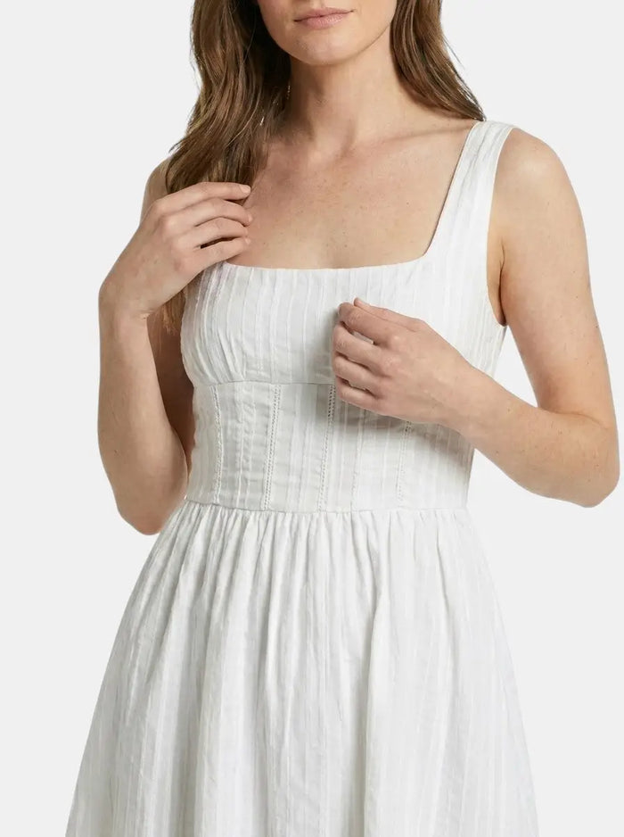 Women's white organic cotton mini summer dress with ruffles and square neckline, featuring a flowing, elegant design.